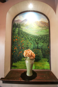 Flower vase in front of orchard mural in alcove